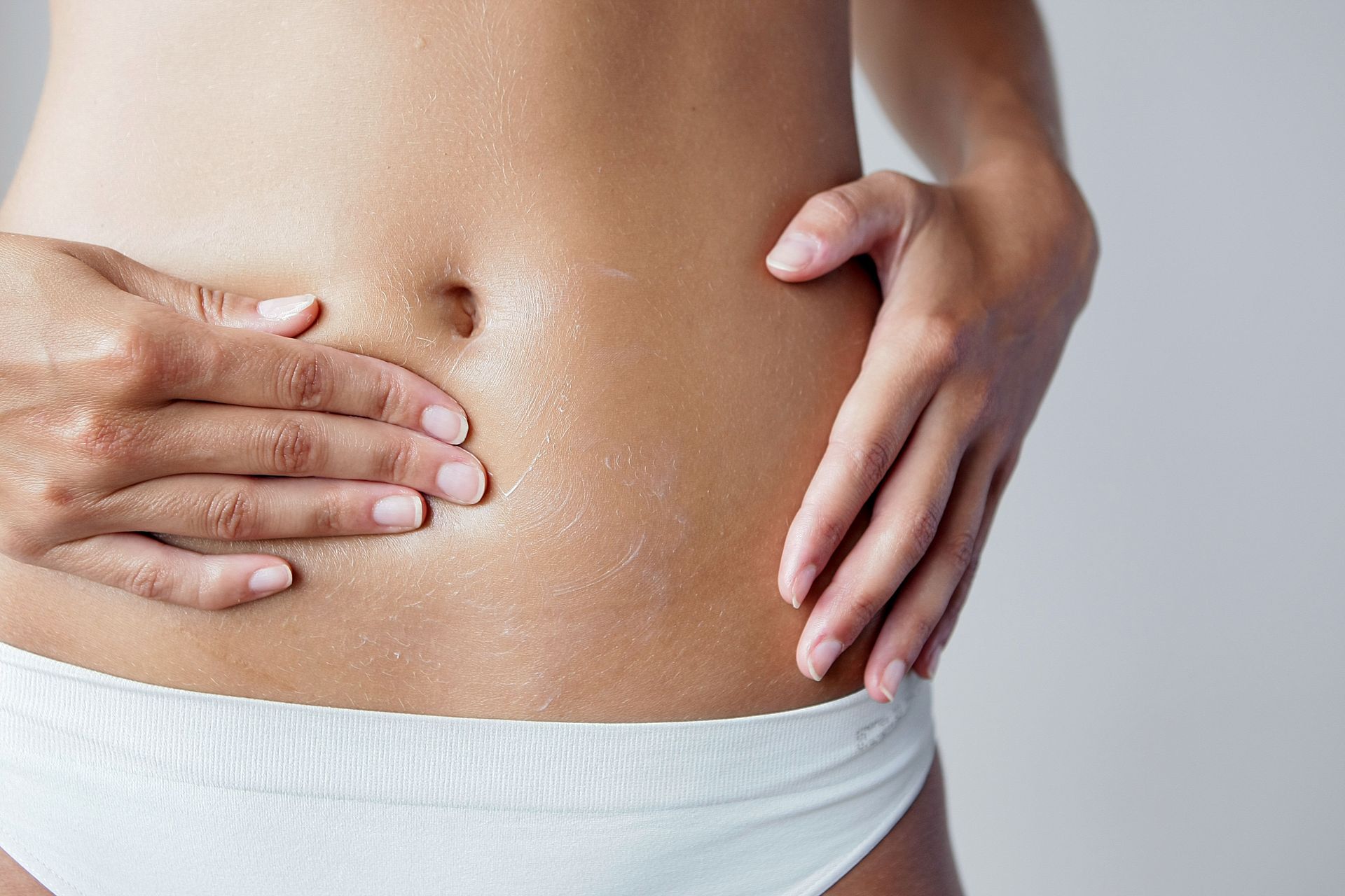 Une femme appliquant de la crème sur son ventre
