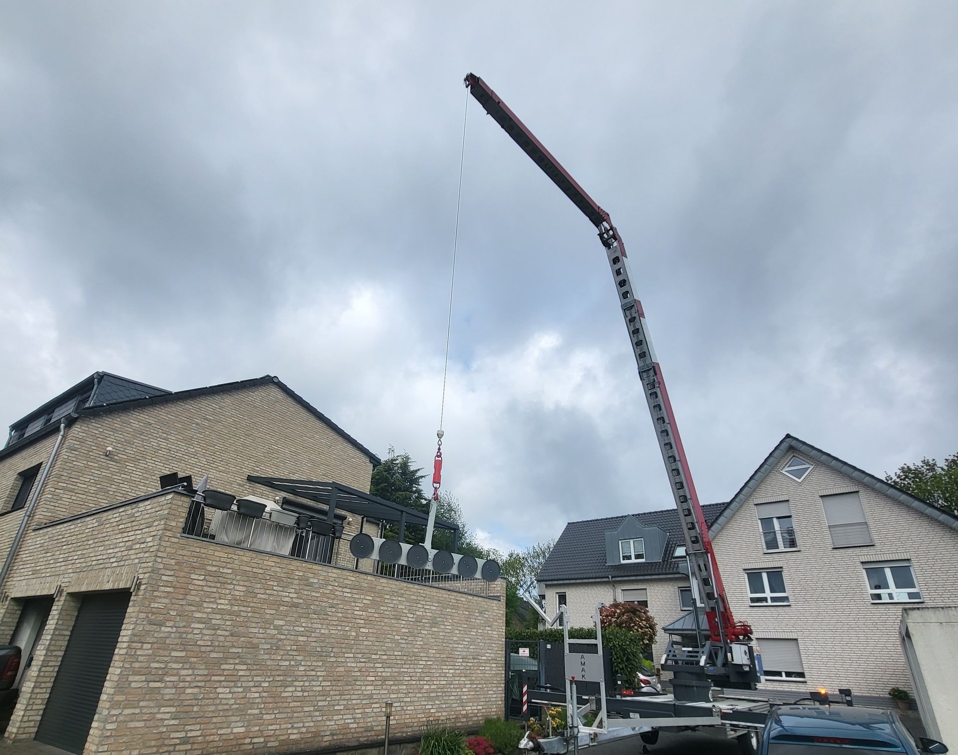 Ein großer Kran hisst eine Flagge vor einem Backsteingebäude.
