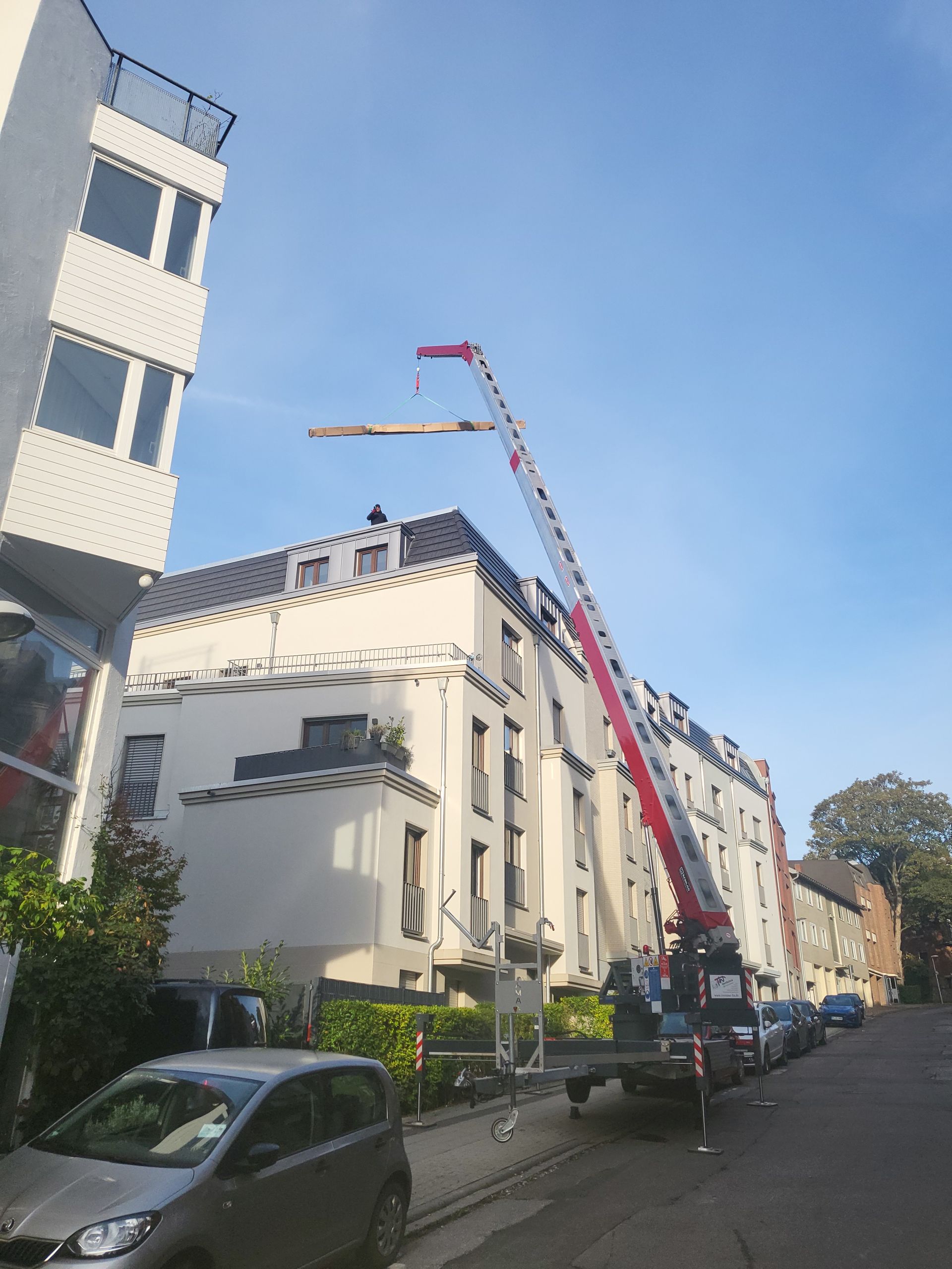Ein Kran wird verwendet, um ein Stück Holz auf ein Gebäude zu heben