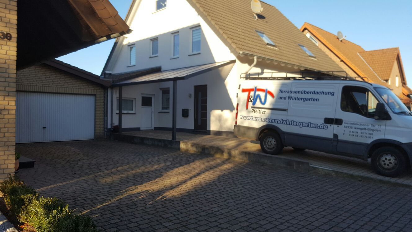 Ein weißes Haus mit Garage und einem Lieferwagen, der an einem sonnigen Tag in der Einfahrt parkt.