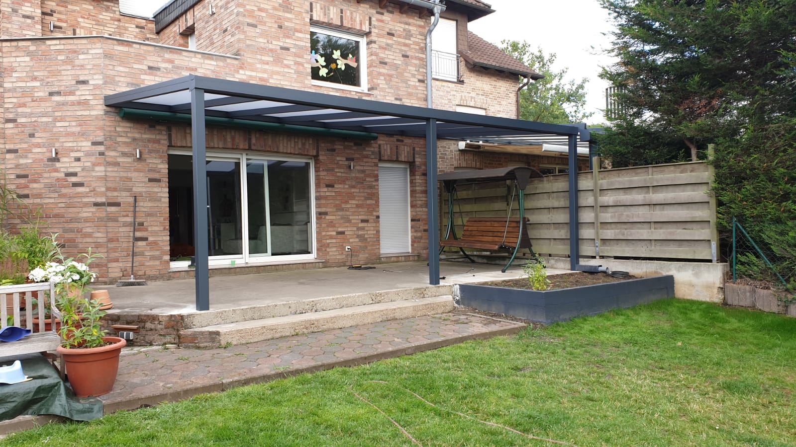 ein Backsteinhaus mit einer überdachten Terrasse im Garten .