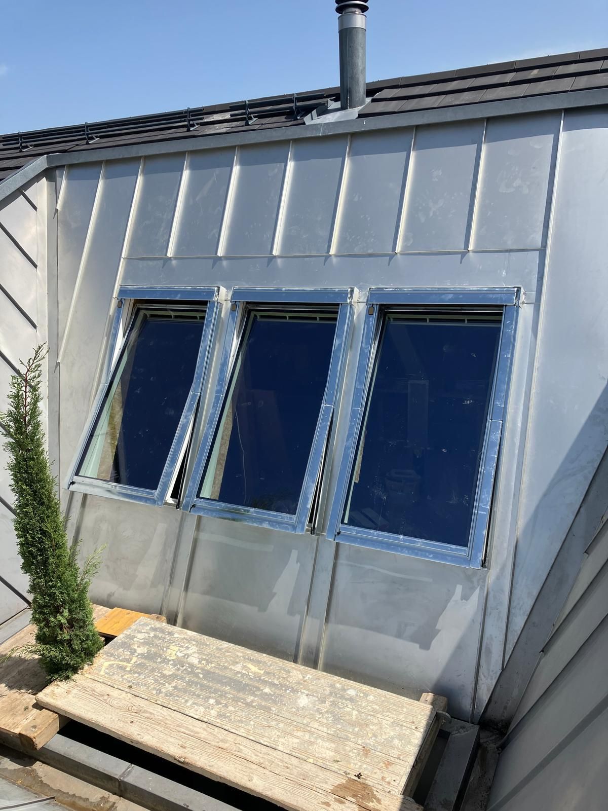 Mur extérieur avec trois fenêtres à cadre bleu et un banc usé en dessous.