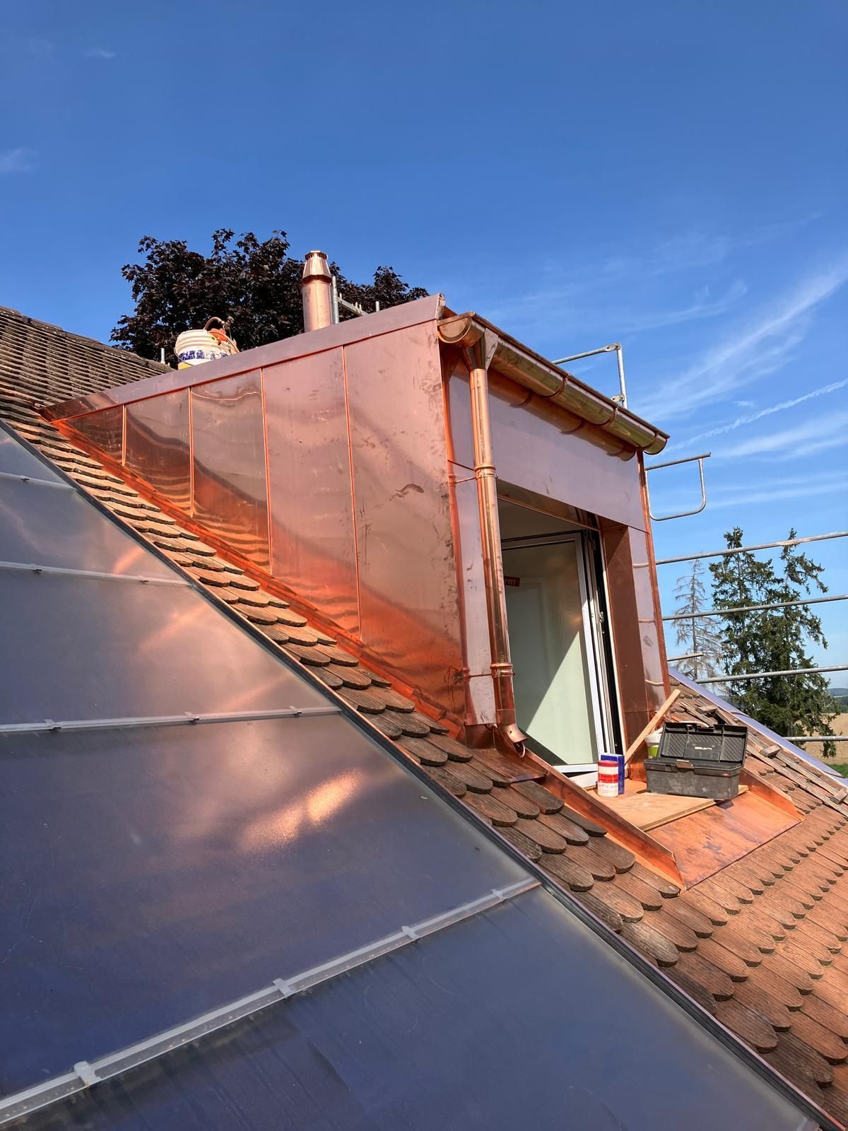 Lucarne en construction avec isolation rose et panneaux solaires sous un ciel bleu