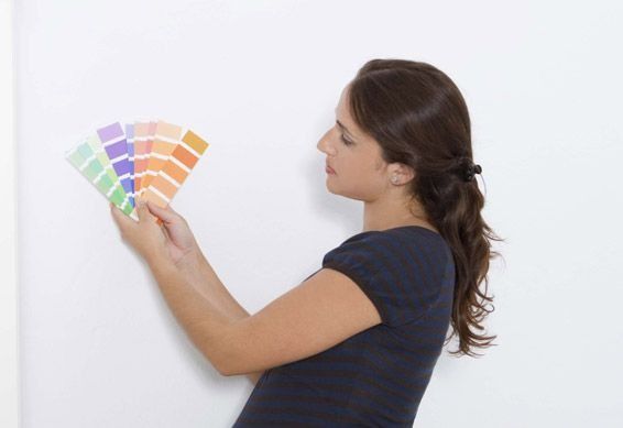 Latas de pintura y pinceles con un abanico de colores en el fondo