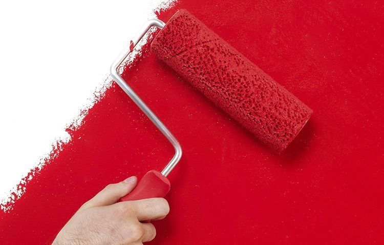 Una persona está pintando una pared con un rodillo de pintura roja.