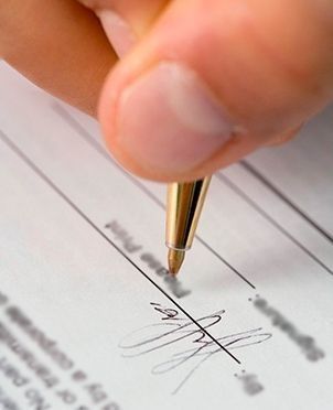 Mano firmando un documento con una pluma dorada, enfatizando la firma.