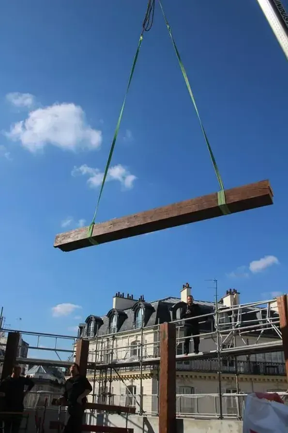 Pose d'une poutre en bois sur le chantier de Pink Mamma