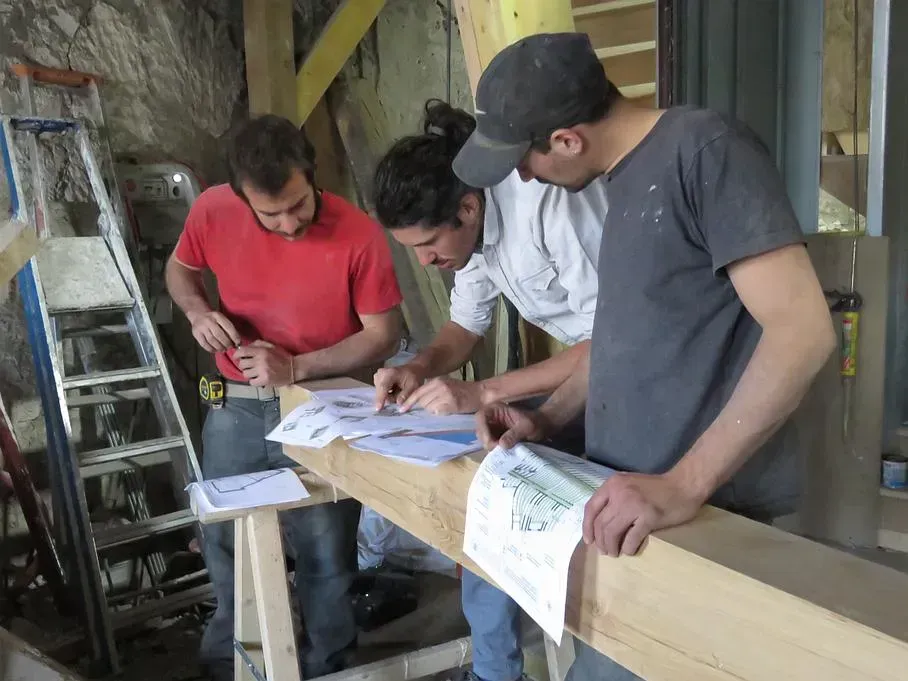 Trois employés analysant une poutre de bois