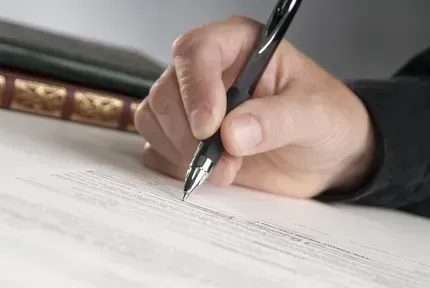 Ein Dokument wird auf einem Schreibtisch mit einem Stift handsigniert.
