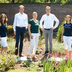 Eine Gruppe von Menschen posiert in einem Garten für ein Foto.