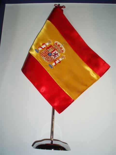 Una pequeña bandera española sobre un soporte de metal.