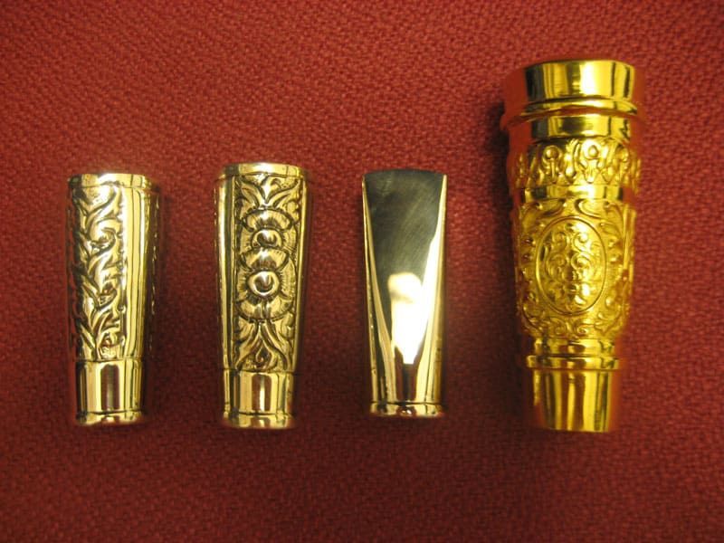 Cuatro objetos dorados están alineados sobre una superficie roja.