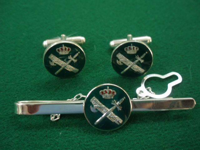 Un par de gemelos y un clip de corbata sobre una superficie verde