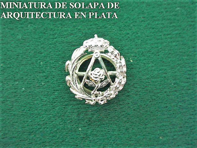 A silver emblem on a green surface that says miniatura de solapa de arquitectura en plata