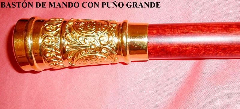 Un bastón de mando con puno grande de caña sobre un paño rosa.