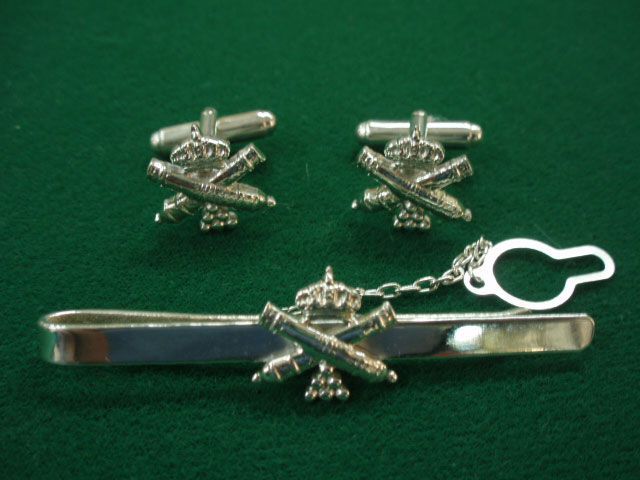 Un par de gemelos y un clip de corbata sobre una superficie verde