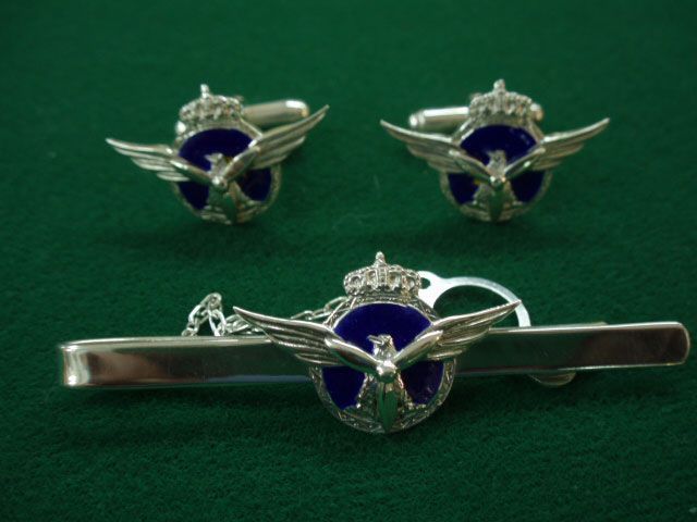 Un par de gemelos y un pasador de corbata sobre una tela verde.