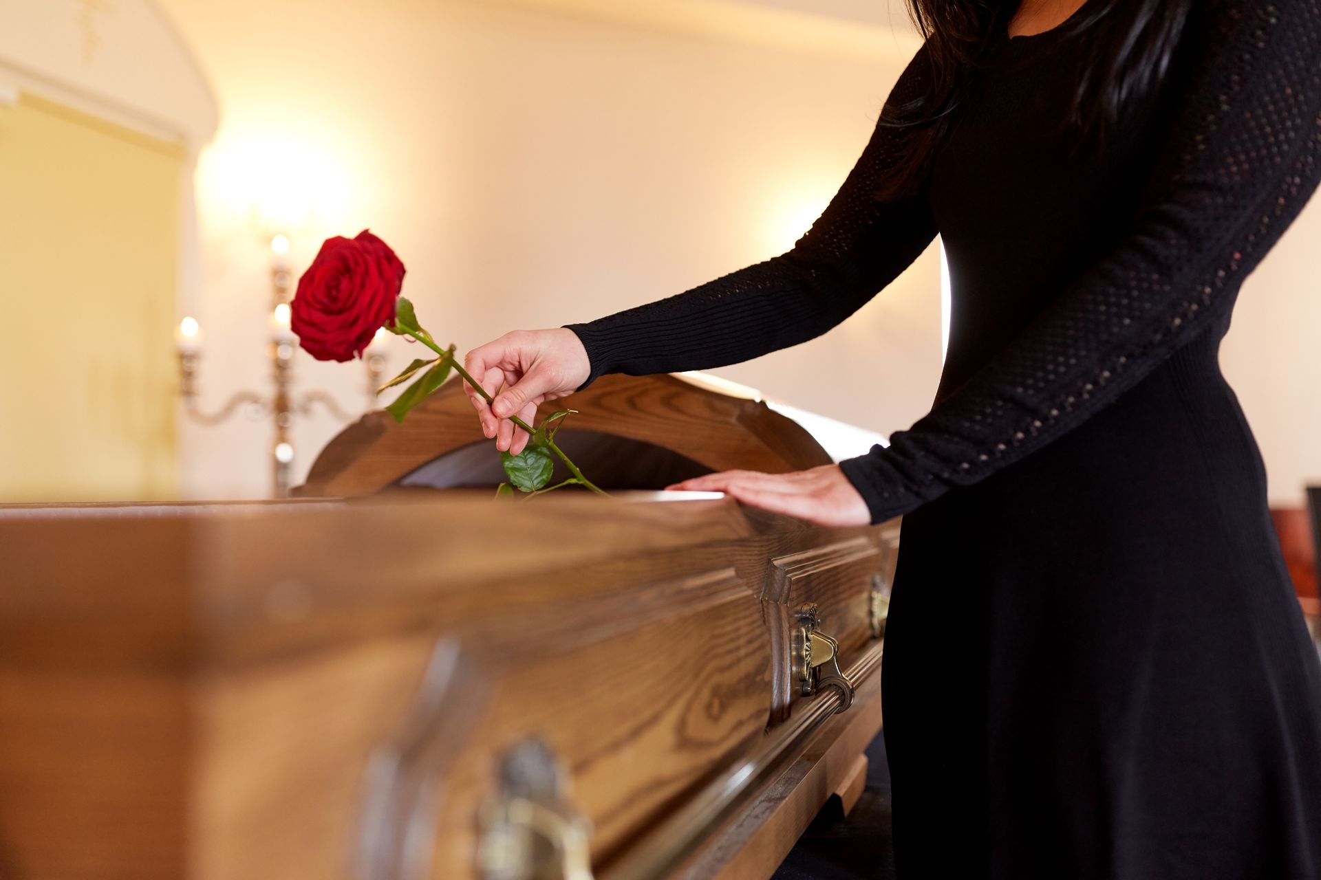 Une personne pose une rose rouge dans un cercueil.