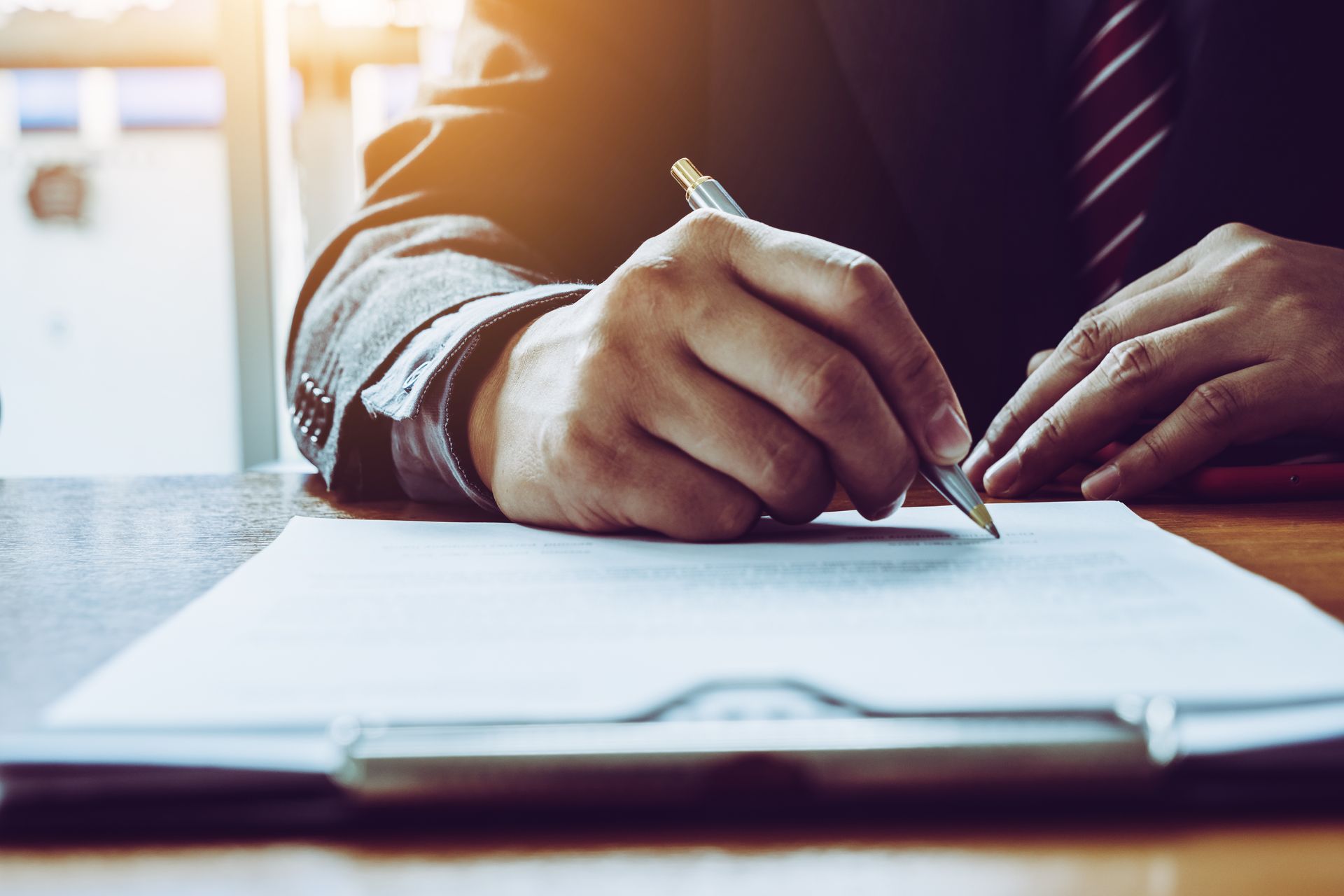 Une personne tenant un stylo, rédige un document.