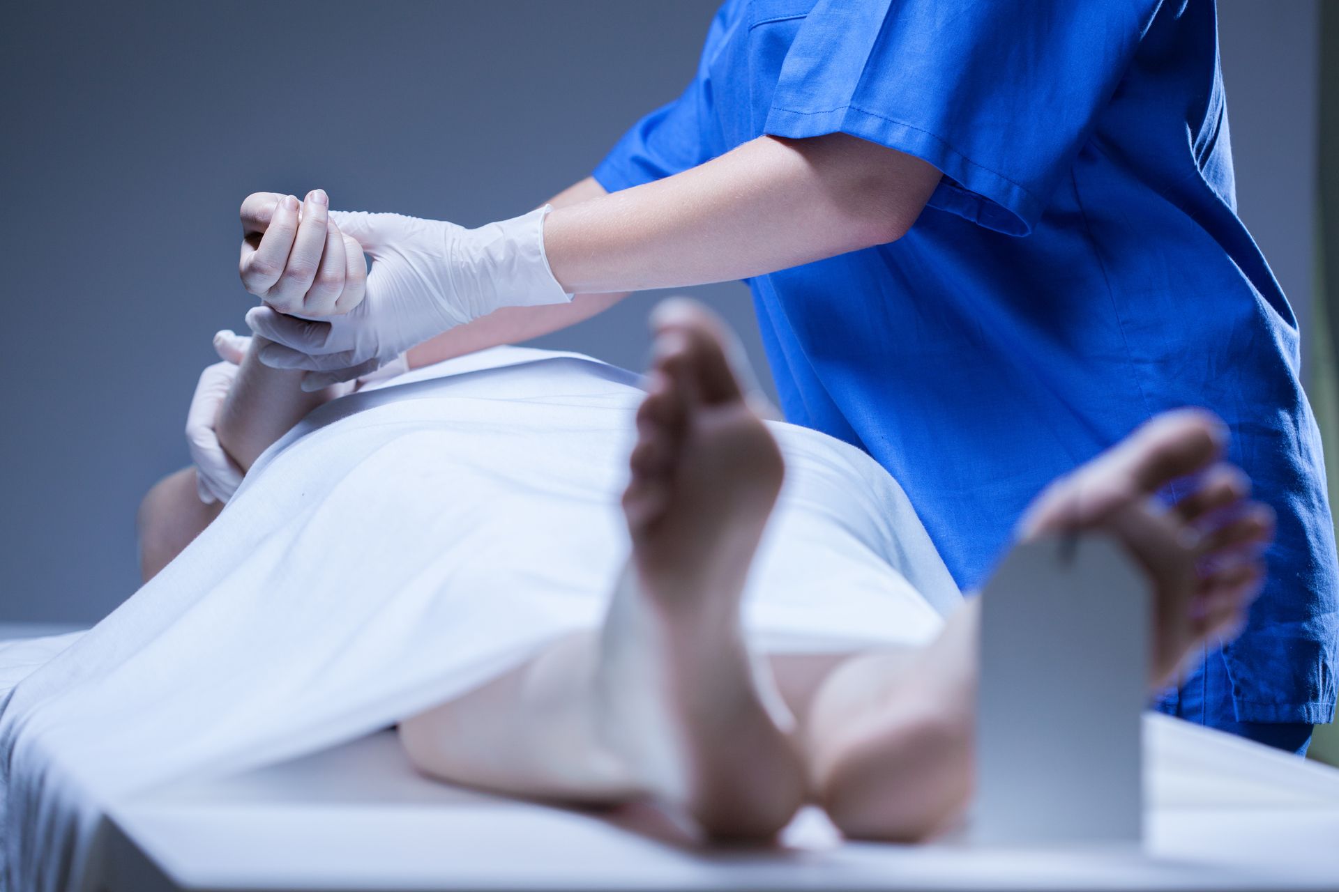 Un thanatopracteur manipule le bras d'une personne décédée.