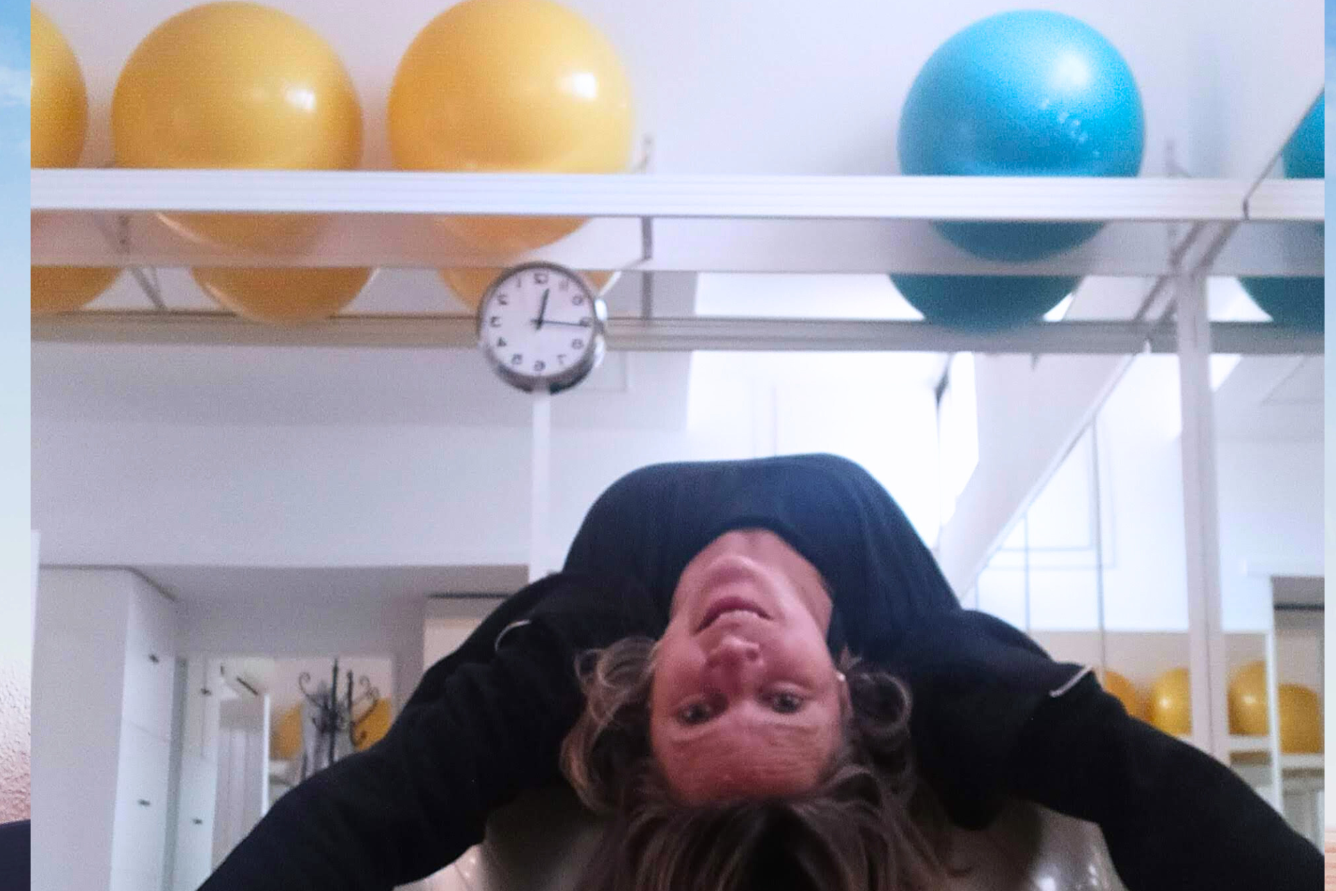 Una mujer está boca abajo frente a un reloj en un gimnasio.