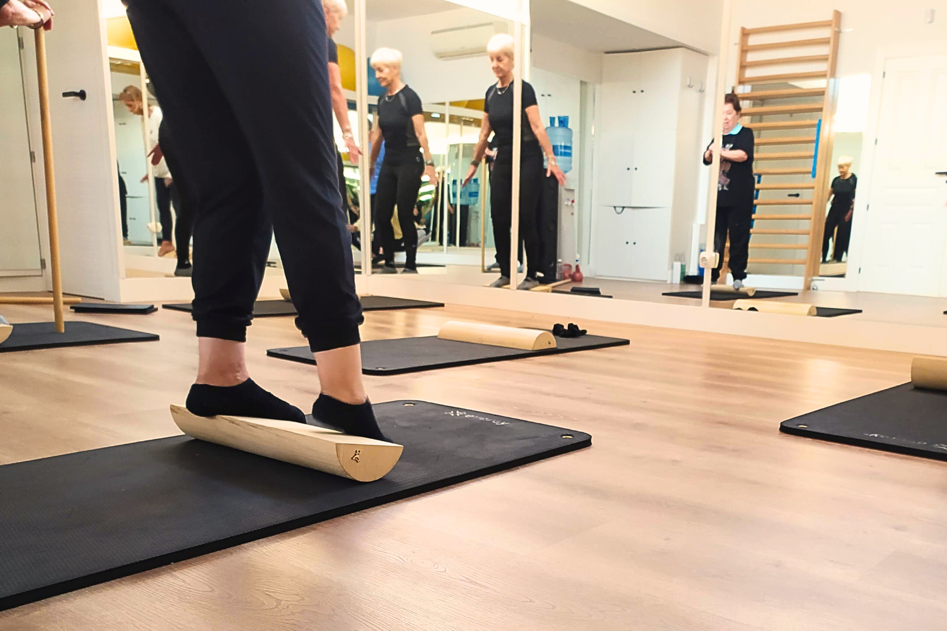 Una persona hace equilibrio sobre una tabla de madera en un gimnasio.