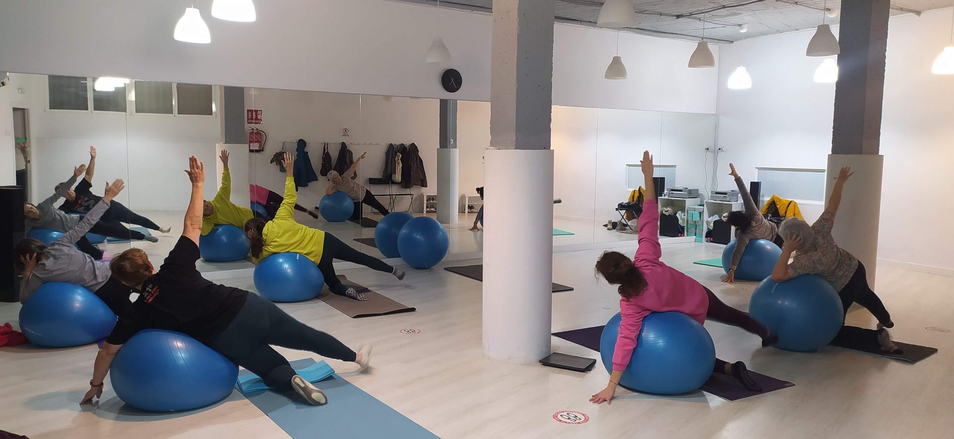 Un grupo de personas está haciendo ejercicios con pelotas de ejercicio en un gimnasio.