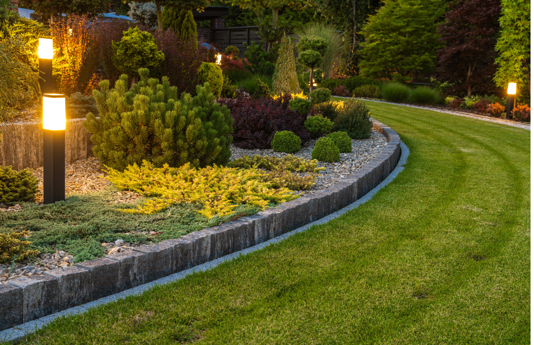Un jardin avec une pelouse verte luxuriante et une bordure en pierre.