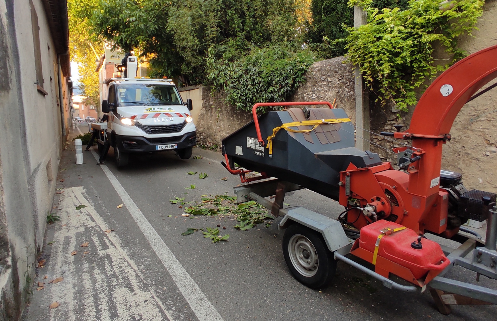 Une machine rouge et noire est garée sur le bord de la route à côté d'une camionnette blanche.