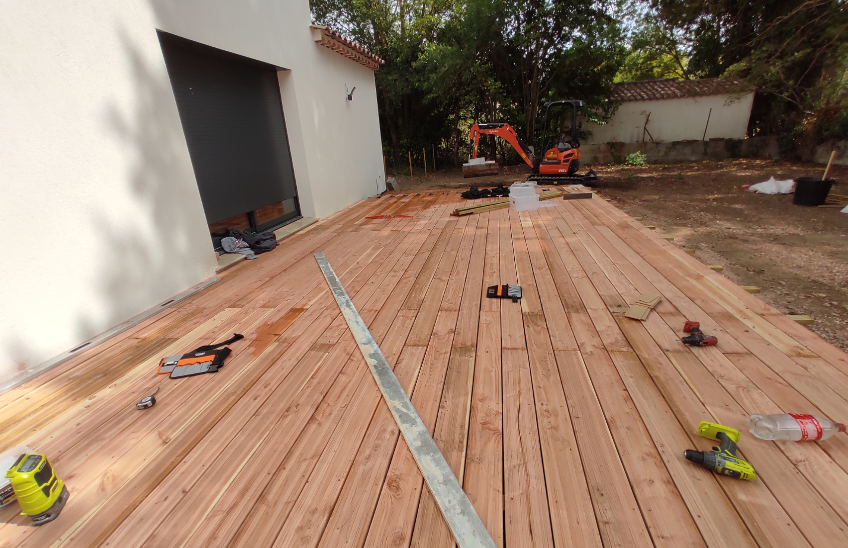 Une terrasse en bois est en cours de construction dans une cour arrière.