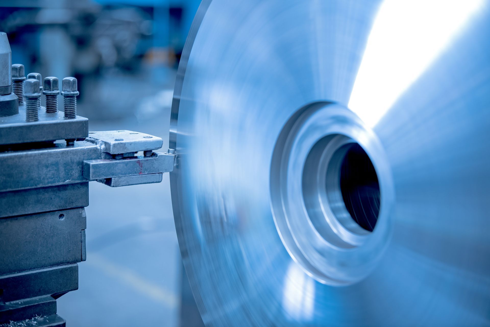 Eine Metalldrehmaschine bearbeitet eine Messingstange, dabei sprühen Funken in einer Industriewerkstatt.