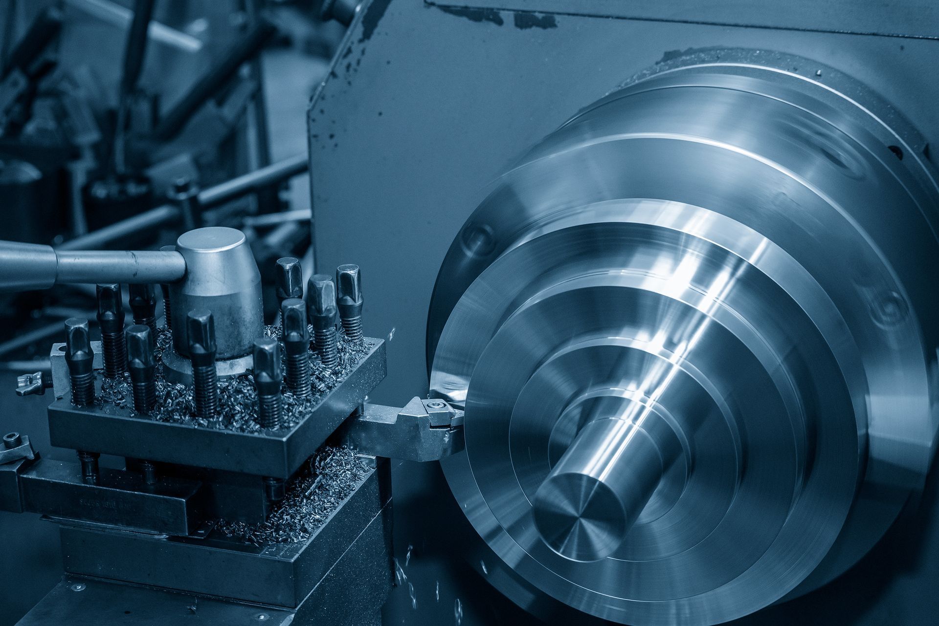 CNC-Drehmaschine bearbeitet ein glänzendes Metallteil in einer bläulich getönten Werkstatt