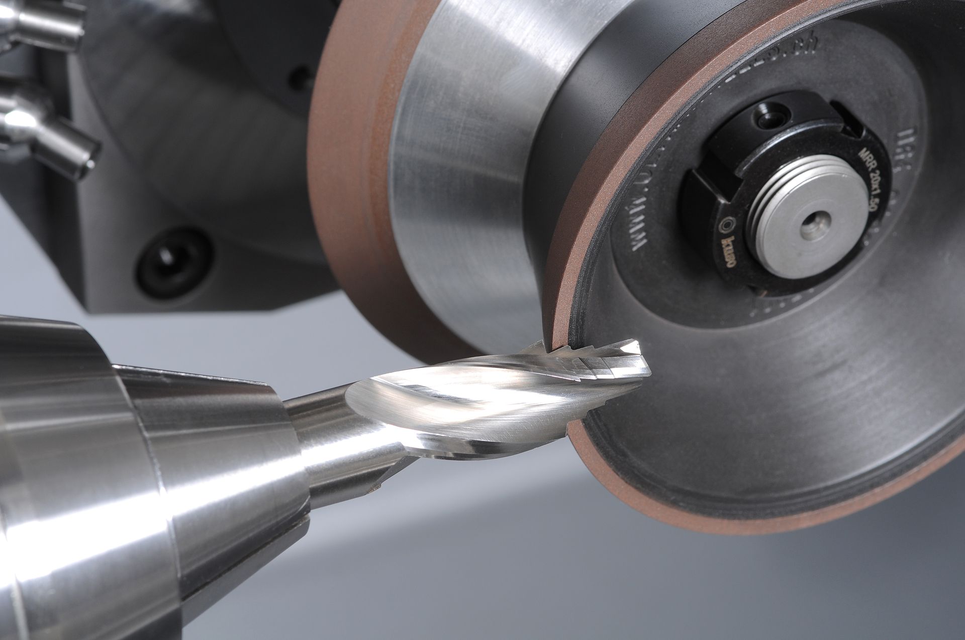 Arbeiter bedient eine Metalldrehmaschine in einer Werkstatt, umgeben von rotierenden Maschinen und bekleidet mit einem blauen Overall.