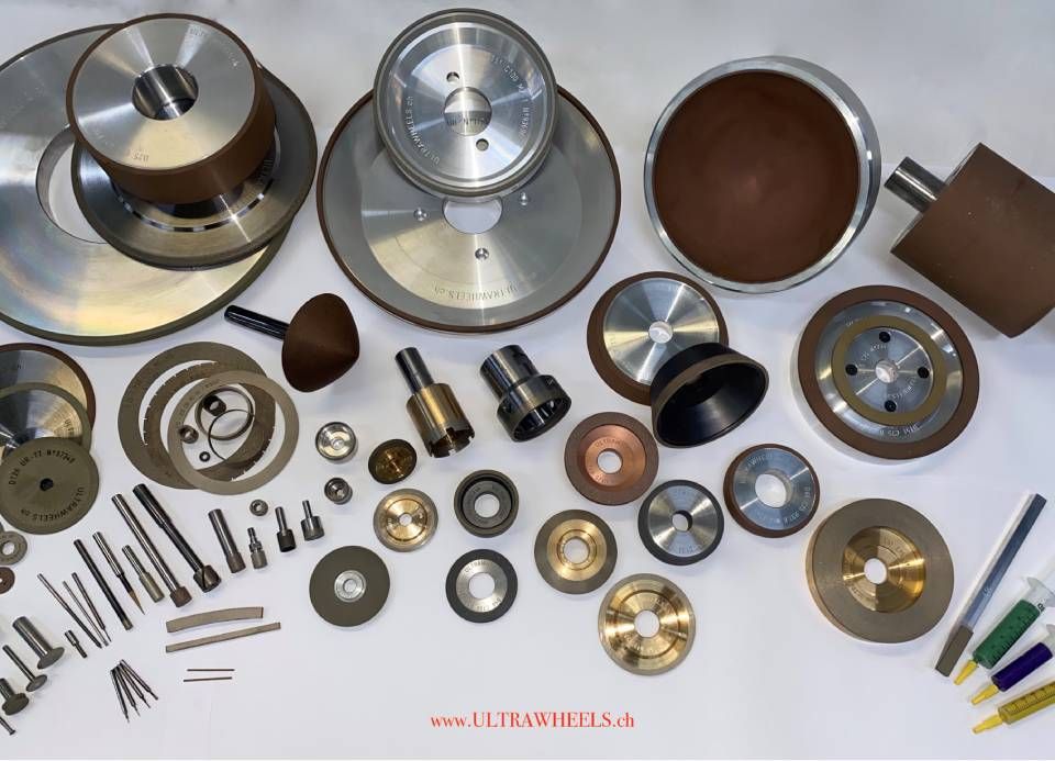 Verschiedene Maschinenteile aus Metall und Kunststoff, Zahnräder, Scheiben, Wellen und Werkzeuge, angeordnet auf weissem Hintergrund