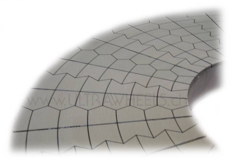 Gebogene Nahaufnahme einer gefliesten oder steinernen Oberfläche mit geometrischem Muster und einem dunklen Ausschnitt auf der rechten Seite.
