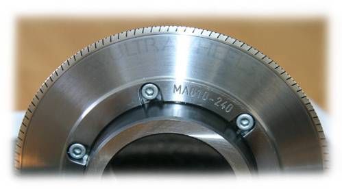 Eine Metalldrehmaschine bearbeitet eine Messingstange, dabei sprühen Funken in einer Industriewerkstatt.