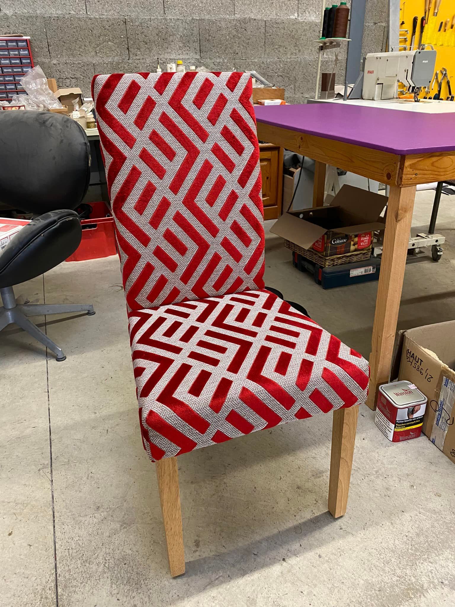 Chaise rembourrée à motif géométrique rouge et blanc ; pieds en bois clair. Mise en scène dans un atelier.