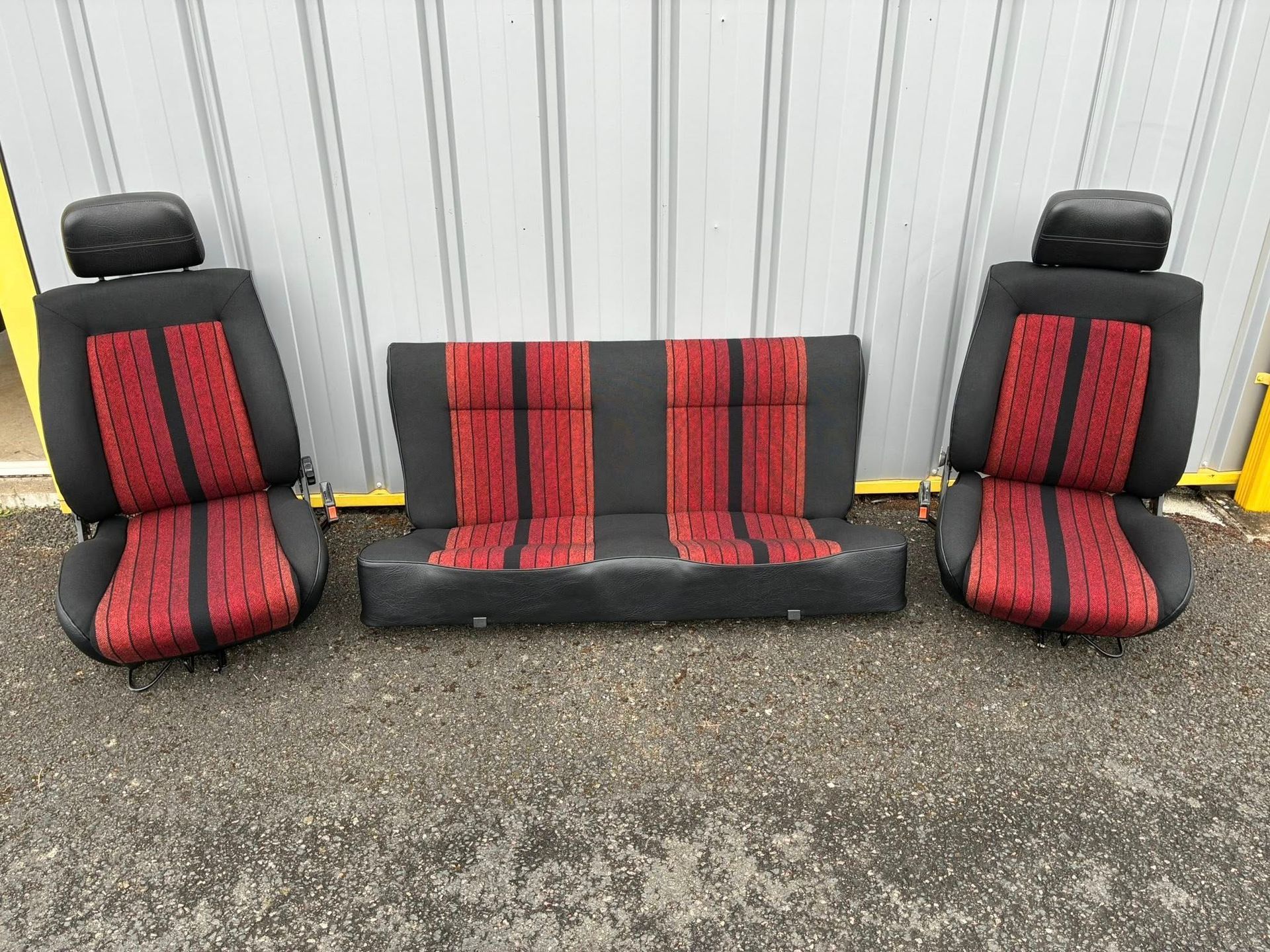 Gros plan sur un siège auto en cuir noir avec des coutures marron apparentes.