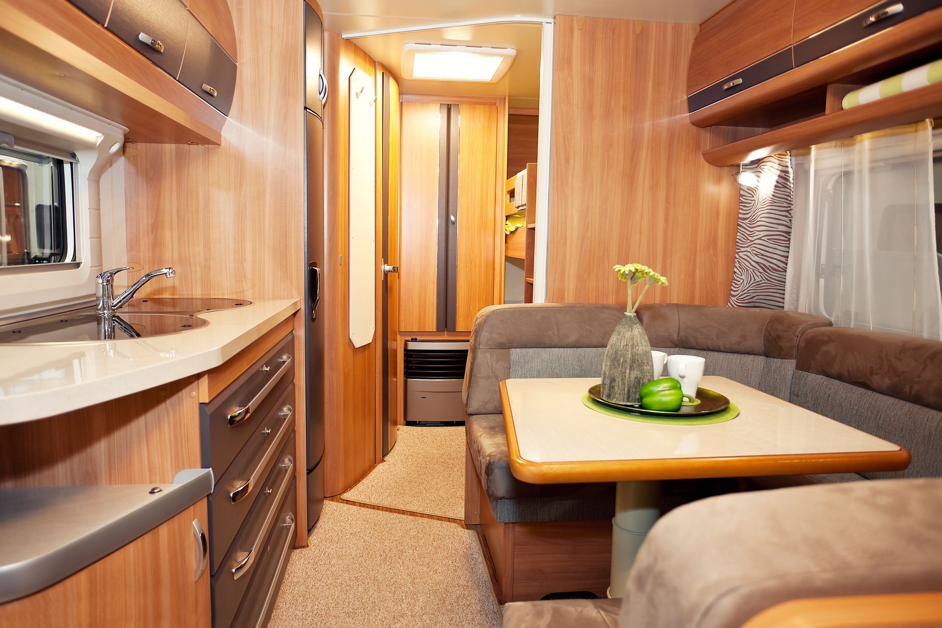 Intérieur d'un camping-car avec lambris, une cuisine, un coin repas et un couloir menant à l'arrière.