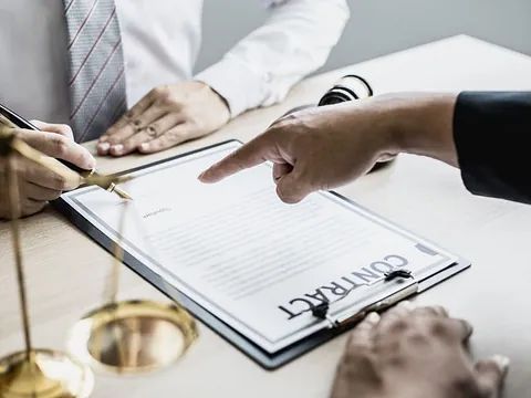 Una persona está señalando un portapapeles que contiene un contrato.