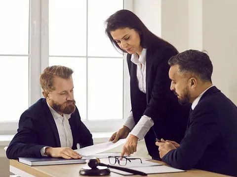 Un grupo de personas está sentada en una mesa mirando papeles.