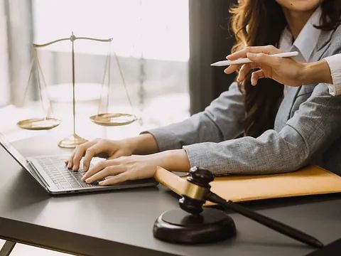 Una mujer está sentada en un escritorio utilizando una computadora portátil.