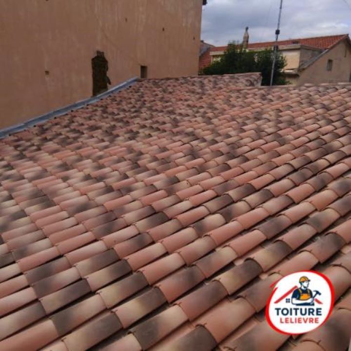 Vue en plongée d'un toit de tuiles en terre cuite nouvellement installé contre le mur d'un bâtiment.