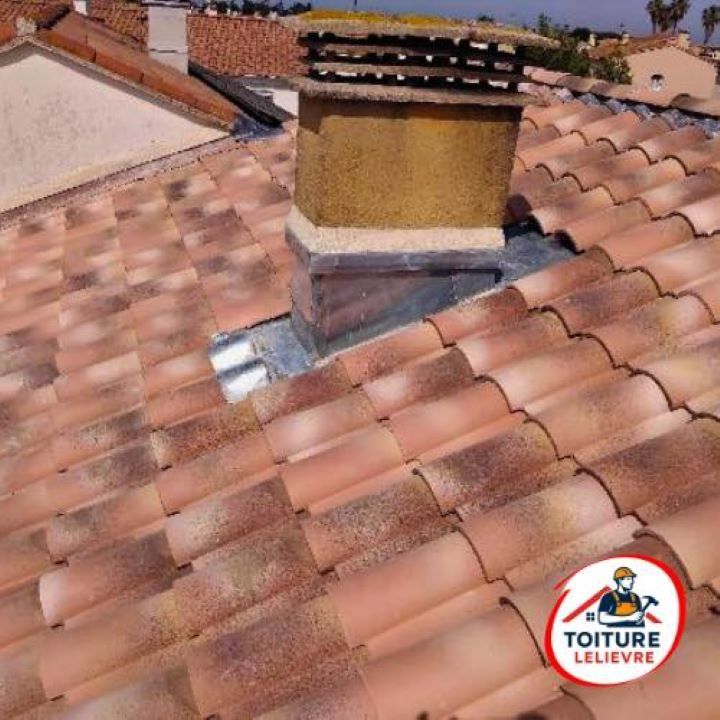 Un toit en tuiles de terre cuite avec une cheminée centrale, orné de solins en plomb à la base.