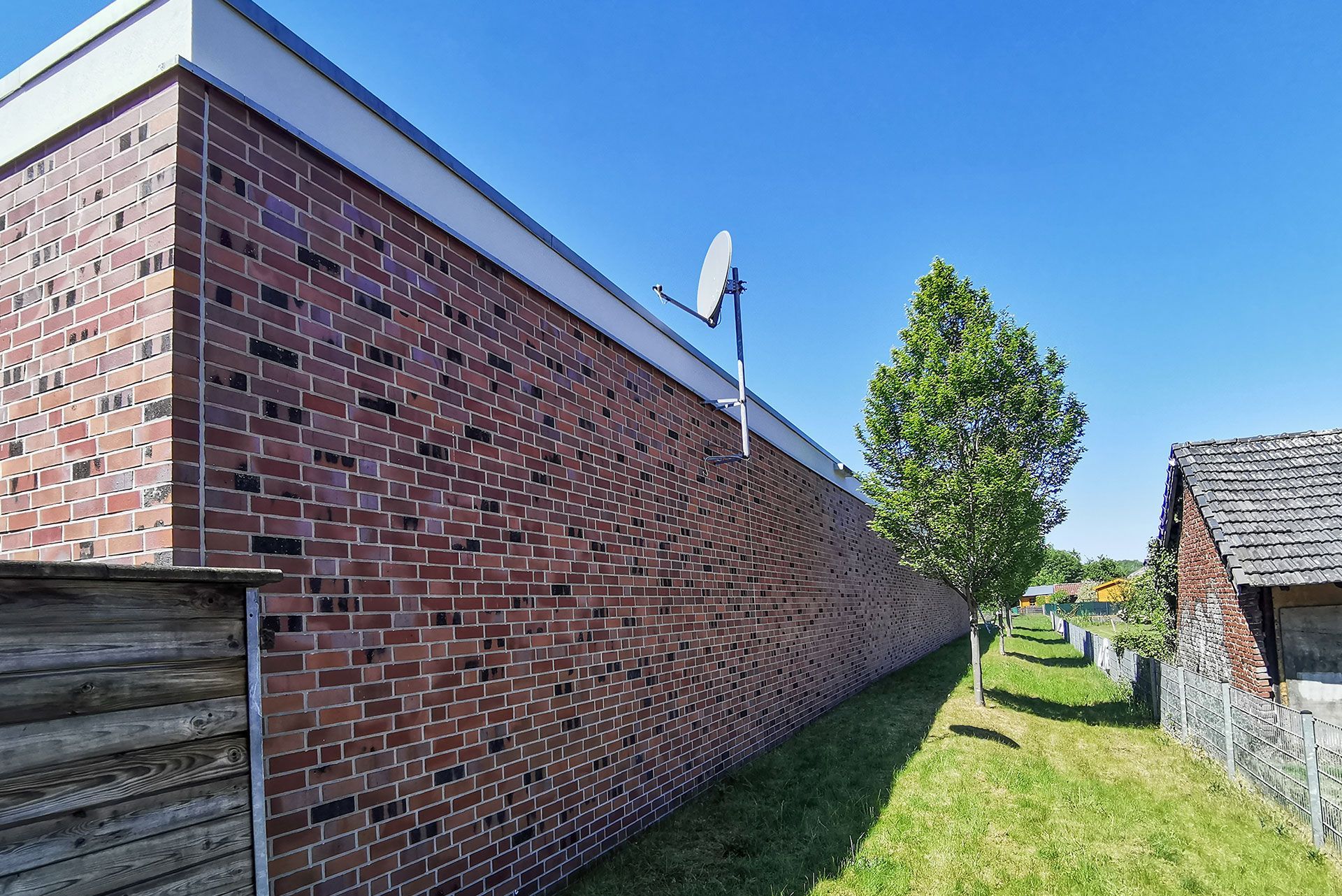 eine Backsteinmauer mit einer Satellitenschüssel darauf.