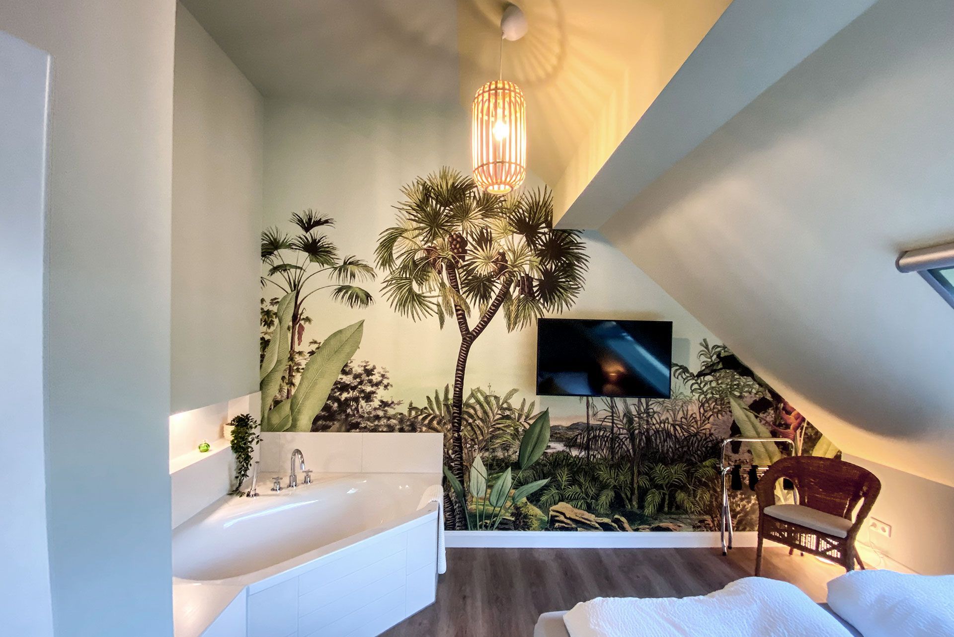 Bad mit Badewanne und einem Fernseher an einer tapezierten Wand.