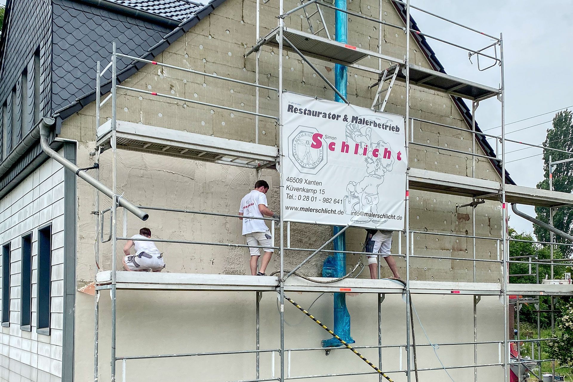 Eine Gruppe von Menschen arbeitet an der Seite eines Gebäudes.