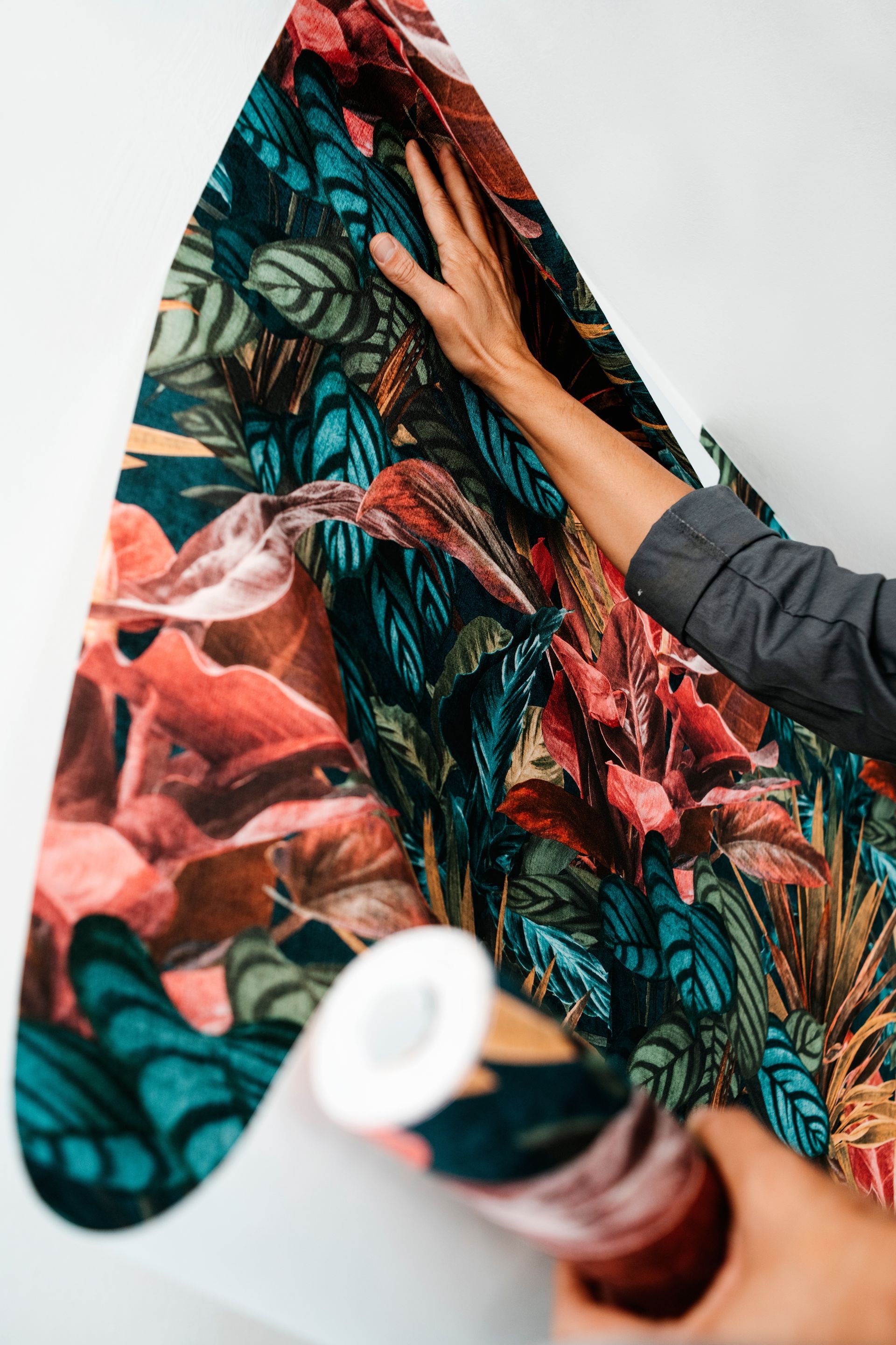 Eine Person bringt eine gemusterte Tapete an die Wand