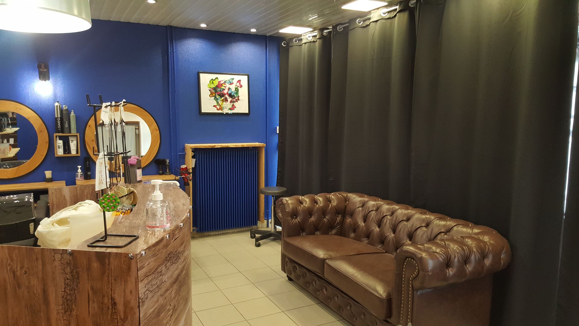 Espace attente du salon de coiffure avec canapé et comptoir en bois