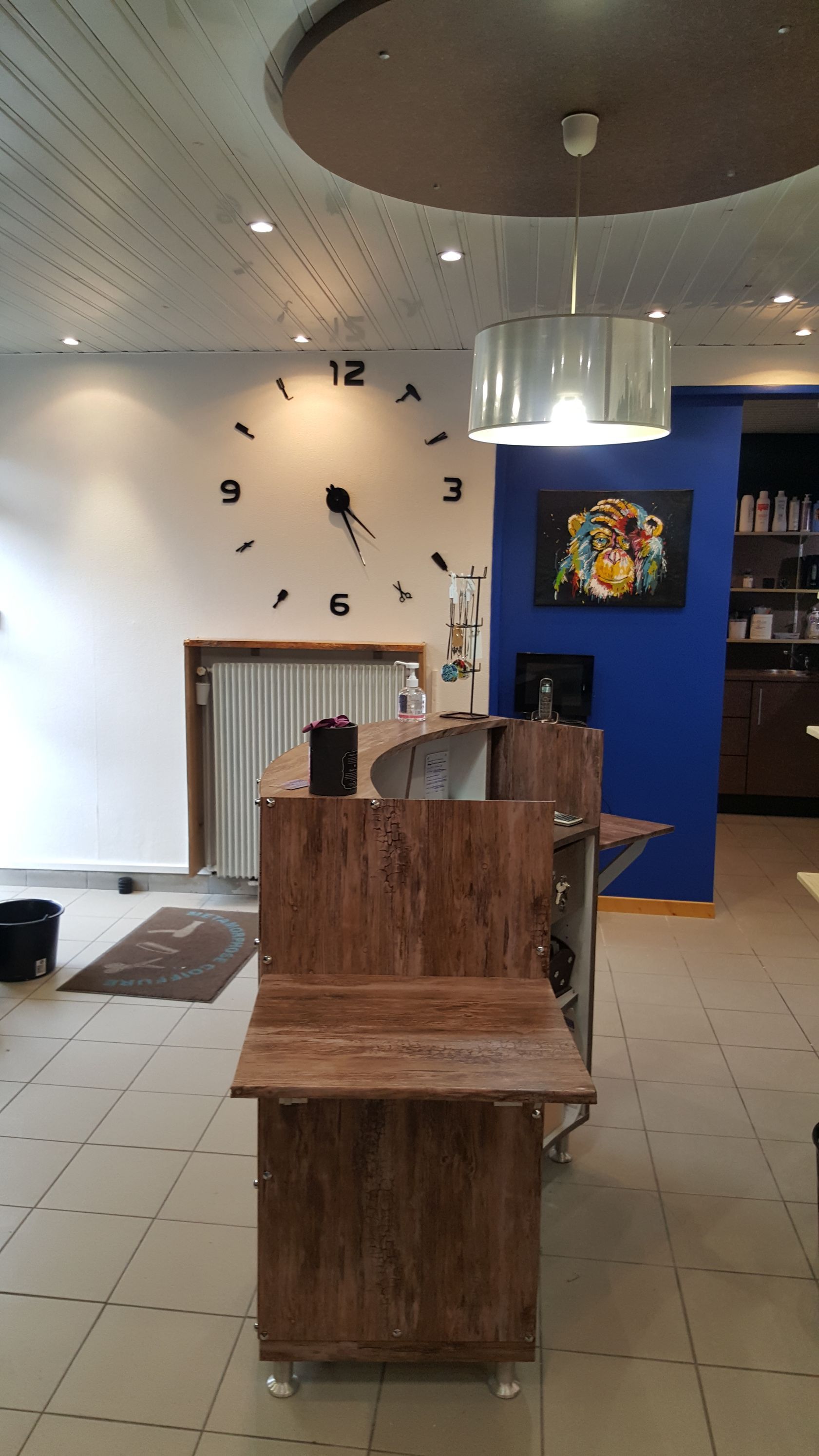 Accueil du salon de coiffure avec comptoir et horloge